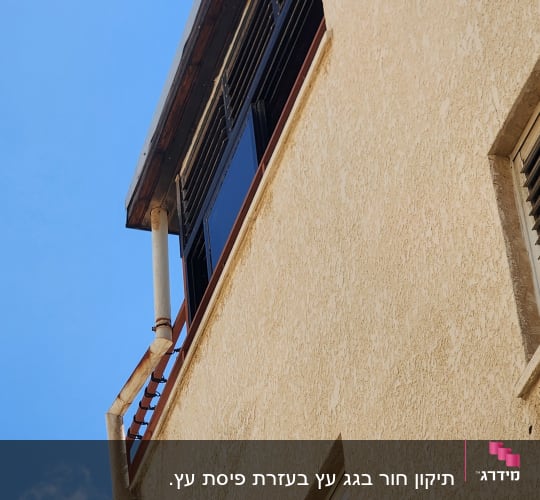גג עם מרזב חלוד וחלונות תריסים